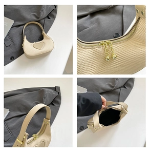 Details der cremefarbenen Sichel-Webtasche mit Herz-Patch, Gold-Zippern und Kugel-Anhängern