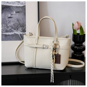 Detail of off-white lychee texture bucket bag with woven rope and charm decoration