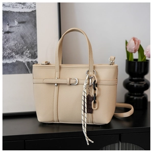 Detailed macro of beige lychee texture leather bucket bag with decorative chocolate charm
