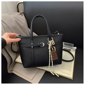 Close-up of black lychee texture leather bucket bag with decorative metal buckle and charm