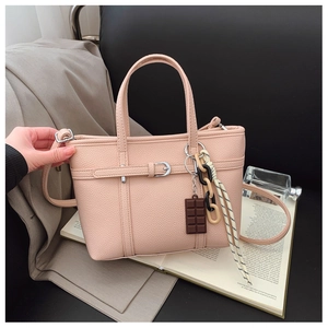 Detail of pink lychee textured bucket bag with decorative scarf and cute charms