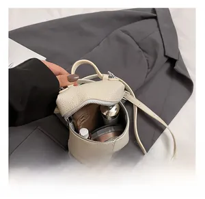 Detail view of cream lychee texture mini bag interior holding phone and cosmetics
