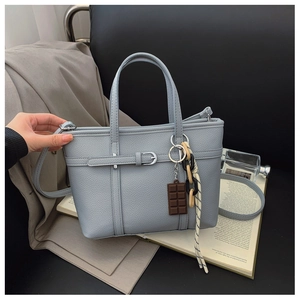 Close-up of light blue lychee pattern leather tote bag with silver buckle and charm
