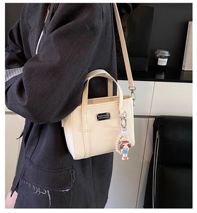 Detailansicht der beigefarbenen Eimer-Tasche mit Leder-Textur und edlem Metall-Logo