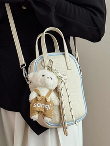Sac bandoulière chic en cuir grainé beige avec bordure bleue et charm ours en peluche