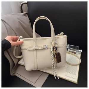 Detail of off-white lychee pattern leather bucket bag with silver buckle and stylish charms