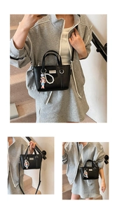 Detailansicht der schwarzen Leder-Eimertasche mit süßem Puppen- und Perlenanhänger-Zubehör