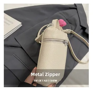 Detail of cream lychee texture handbag with silver hardware zipper and heart charm