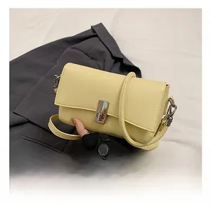 Detail view of a pale yellow rectangular crossbody bag with silver metal buckle closure