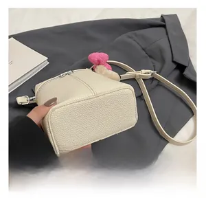 Detail view of cream lychee texture leather crossbody bag with dual silver zippers
