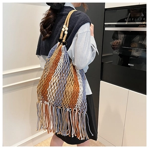 Detailed macro view of bohemian hand-woven tote bag with fringe and wooden bead accents