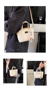 Detailansicht der beigen Eimertasche mit Lederstruktur, Perlenkette und Puppenanhänger