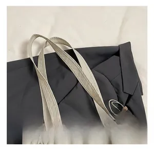 Close-up of wide reinforced straps on a light beige nylon tote bag with durable stitching