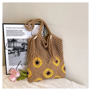 Détail du sac cabas tissé main avec motif de tournesol et charme de gland bohème chic