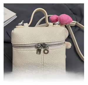 Detailed close-up of off-white lychee grain leather bag with silver double zippers