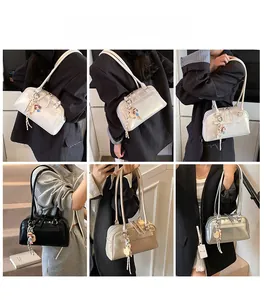 Boston bag shown in white, black, beige and silver with stylish charms and shoulder straps