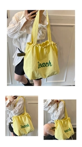 Detail of yellow canvas tote bag with green Beach print and drawstring closure