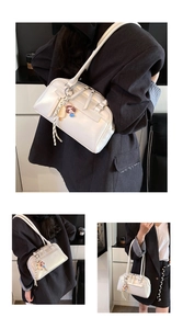 Detail view of pearl white Boston bag with cute charms worn by a model in a gray blazer