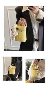 Detail of yellow lychee pattern handbag featuring a cute plush dog pendant and dual zippers