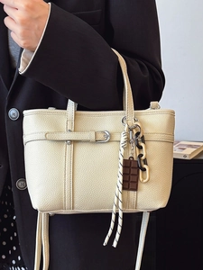 Cream lychee leather bucket bag with decorative charms and adjustable shoulder strap