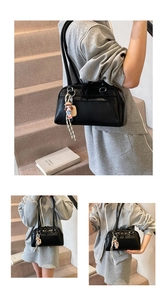 Close-up of black leather Boston bag with dual handles and cute cartoon charm