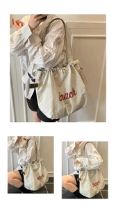 Detail showing creamy white canvas tote bag with red bach lettering and drawstring closure