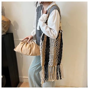 Detail of bohemian woven tote bag with long fringe and decorative wooden bead handles