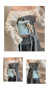 Detail of light blue litchi pattern leather handbag with cute puppy plush charm pendant