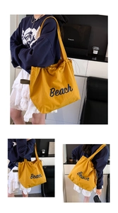 Macro detail of a yellow canvas beach tote bag with blue lettering and drawstring closure