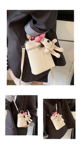 Detail view of cream crossbody bag with lychee texture and cute puppy plush pendant