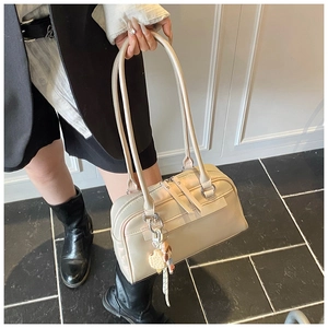 Detail of light beige Boston bag with long handles and waffle charm on zipper