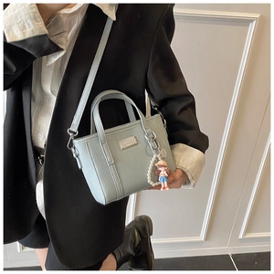 Detailaufnahme der hellblauen Eimertasche mit Lychee-Muster und Puppenanhänger