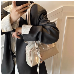 Creamy white shoulder bag with smooth pearlescent finish and cute bear charm detail