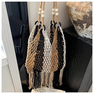 Detail of bohemian tricolor woven tote bag with cotton fringes and wooden bead handle