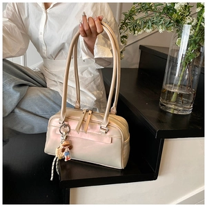 Close-up of pearl white Boston bag featuring dual long handles and a cute cartoon charm