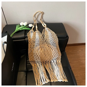 Detailed macro view of bohemian woven tote bag with cotton fringes and wooden bead accents