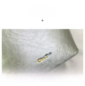 Close-up of silver pebble grain leather bucket bag featuring a gold embossed logo