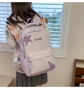Détail d'un sac à dos en nylon lilas avec écusson étoile et peluche suspendue