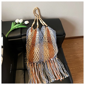 Detail of colorful woven tote with stripes, wooden beads, and long tassels on a sofa