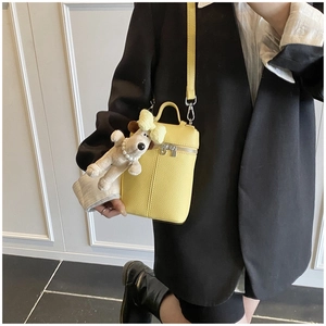 Detail of yellow lychee texture handbag with cute puppy charm and thin shoulder strap