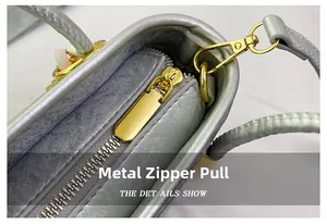 Detailed close-up of the smooth metal zipper pull and gold hardware on the silver PU bucket bag