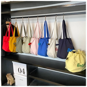 Detailed row of colorful drawstring canvas tote bags with Beach text print on shelves