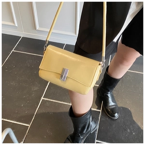 Detail view of a yellow oil wax leather crossbody bag with silver metallic buckle on model