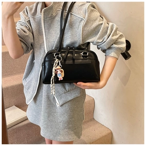 Detail of black Boston shoulder bag featuring long straps and a cute cartoon charm accessory