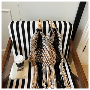 Close-up of bohemian woven tote bag with wooden beads and tassels on striped chair