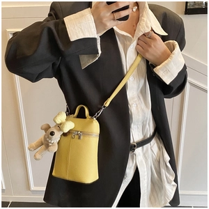 Detail of yellow lychee pattern mini bag with cute dog pendant worn with a black blazer