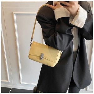 Detail of light yellow oil wax leather crossbody bag with silver rectangle swivel lock closure