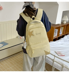 Détail du sac à dos en nylon jaune clair avec patch étoile et broderie soleil