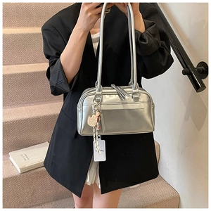 Close-up of shiny silver metallic Boston bag with cute cookie bear charm on a shoulder strap