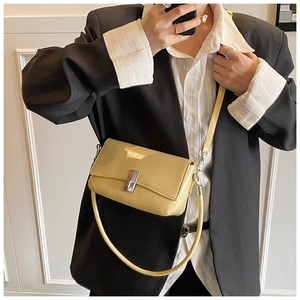 Detail of elegant yellow wax leather square bag with silver metal lock on a black blazer
